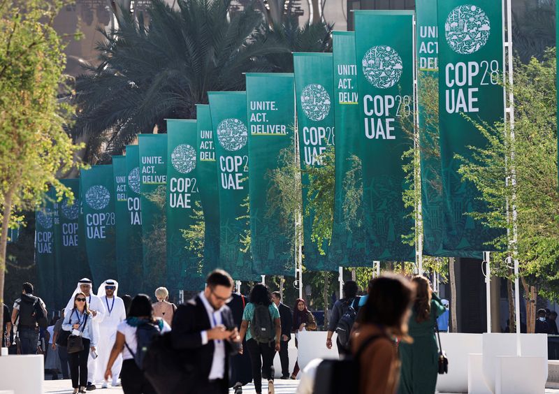 © Reuters. مندوبون يسيرون في موقع انعقاد مؤتمر الأمم المتحدة المعني بتغير المناخ (كوب28) في دبي يوم الجمعة. تصوير: ثائر السوداني - رويترز.
