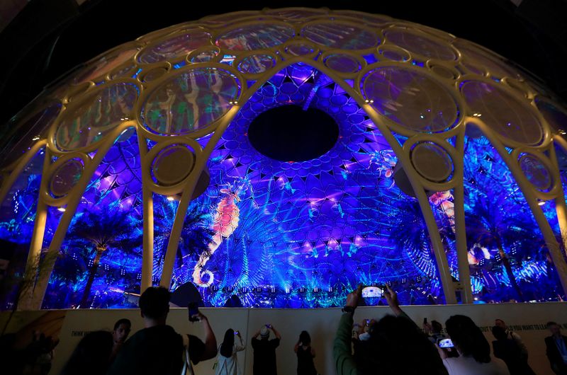 © Reuters. Delegates use their mobile phones to record the projections at the Al Wasl Dome at the Dubai's Expo City during the United Nations Climate Change Conference (COP28) in Dubai, United Arab Emirates, December 9, 2023. REUTERS/Thomas Mukoya