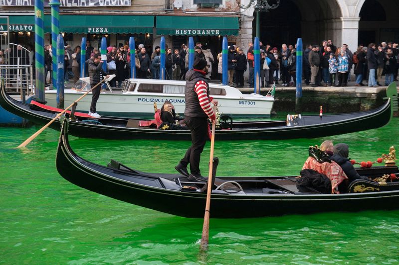 &copy; Reuters. أشخاص يركبون في قاربين في مياه القناة الكبرى بمدينة البندقية بإيطاليا والتي تحولت إلى اللون الأخضر في احتجاج من جانب أعضاء جماعة إكستنكشن ر