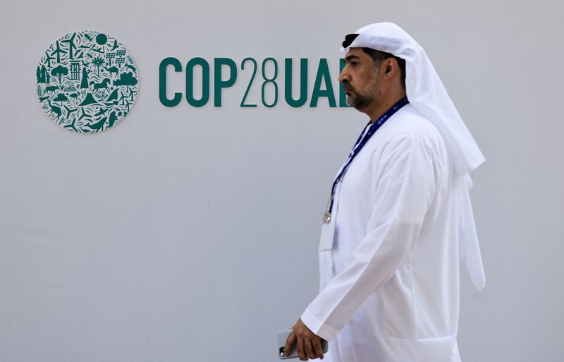 © Reuters. A delegate walks past a logo of the COP28 climate summit in Dubai, United Arab Emirates, December10, 2023. REUTERS/Thaier Al Sudani