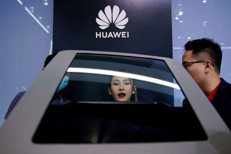 &copy; Reuters. FOTO DE ARCHIVO: Gente comprueba una pantalla cerca de un logotipo de Huawei durante un día para los medios de comunicación en la feria Automotriz de Shanghái en Shanghái, China. 19 de abril 2021. REUTERS/Aly Song/Archivo