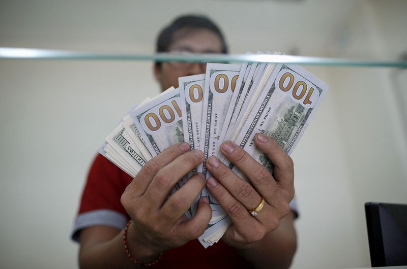 &copy; Reuters. Un bancario conta diverse banconote da 100 dollari a Yangon, in Myanmar. 17 luglio 2015. REUTERS/Soe Zeya Tun/File Photo