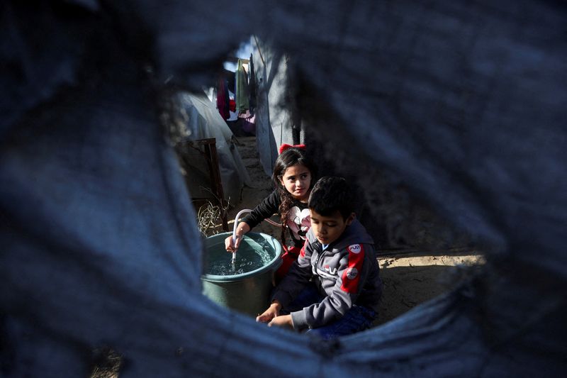 © Reuters. Displaced Palestinian children, who fled their house due to Israeli strikes, shelter in a tent camp, amid the ongoing conflict between Israel and the Palestinian Islamist group Hamas, in Khan Younis in the southern Gaza Strip, December 11, 2023. REUTERS/Ibraheem Abu Mustafa  