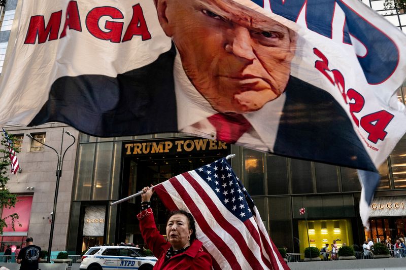 © Reuters. A supporter of former U.S. President Donald Trump holds up a U.S. national flag at Trump Tower in New York City, U.S., October 1, 2023. REUTERS/David 'Dee' Delgado/File Photo