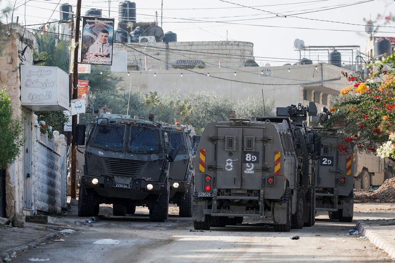 &copy; Reuters. Veicoli militari israeliani fanno manovra su una strada durante un raid a Jenin, nel corso del conflitto in corso tra Israele e il gruppo islamista palestinese Hamas, nella Cisgiordania occupata da Israele, 12 dicembre 2023. REUTERS/Raneen Sawafta