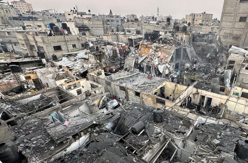 &copy; Reuters. أناس يبحثون تحت ركام منازل دمرتها غارات إسرائيلية على منازل فلسطينيين في رفح جنوب قطاع غزة يوم الثلاثاء. تصوير: رويترز. 