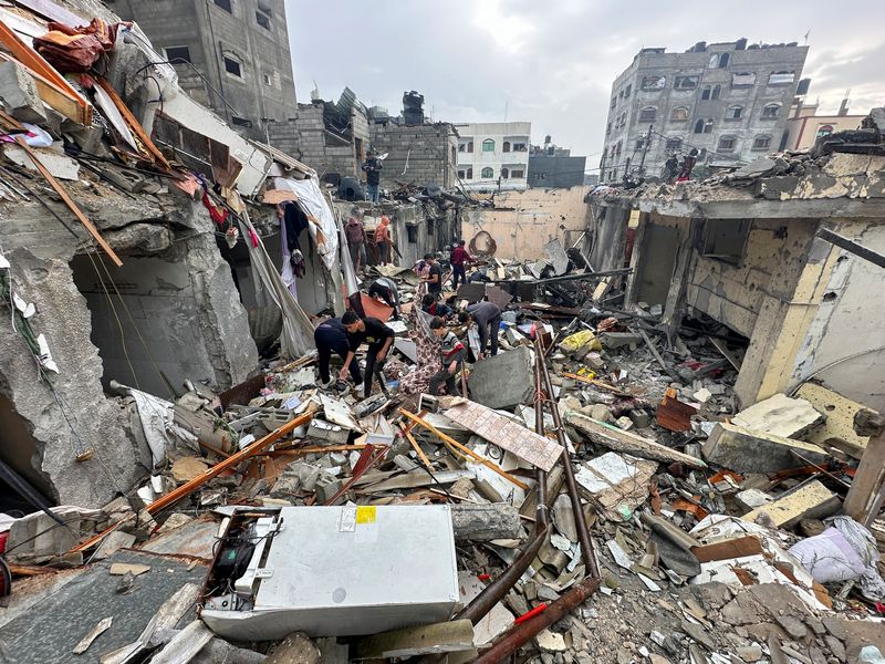 &copy; Reuters. Palestinesi ispezionano il sito di attacchi israeliani, nel corso del conflitto in corso tra Israele e il gruppo islamista palestinese Hamas, a Rafah, nel sud della Striscia di Gaza,13 dicembre 2023. REUTERS/Fadi Shana