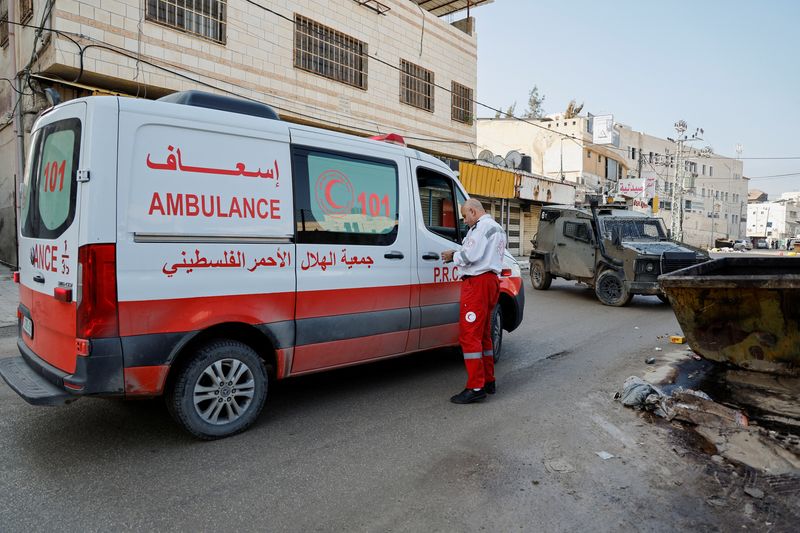 &copy; Reuters. موظف في قطاع الطوارئ يقف خارج سيارة إسعاف تعترضها مركبة عسكرية إسرائيلية أثناء غارة في جنين بالضفة الغربية المحتلة يوم 12 ديسمبر كانون الأول