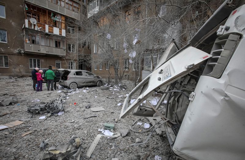© Reuters. سكان محليون يقفون بالقرب من مبنى سكني وسيارات تضررت خلال هجوم صاروخي روسي في خاركيف بأوكرانيا في السادس من ديسمبر كانون الأول 2023. تصوير: فياتشيسلاف ماديفسكي - رويترز.
