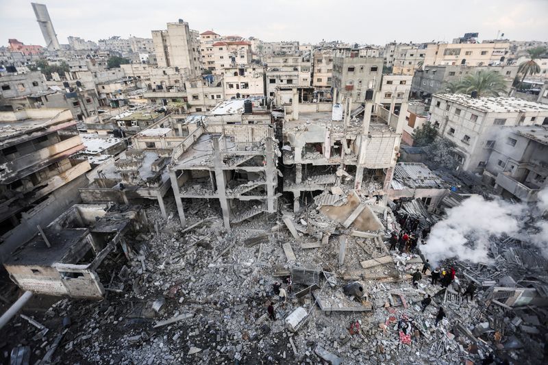 &copy; Reuters. Palestinos se reúnen mientras se levanta humo en el lugar de los ataques israelíes contra casas en Jan Yunis, en el sur de la Franja de Gaza. 14 de diciembre de 2023. REUTERS/Ibraheem Abu Mustafa