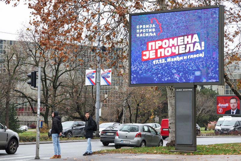 &copy; Reuters. People stand next to a pre-election billboard of the opposition coalition 'Serbia Against Violence'  in Belgrade, Serbia, December 14, 2023. REUTERS/Zorana Jevtic