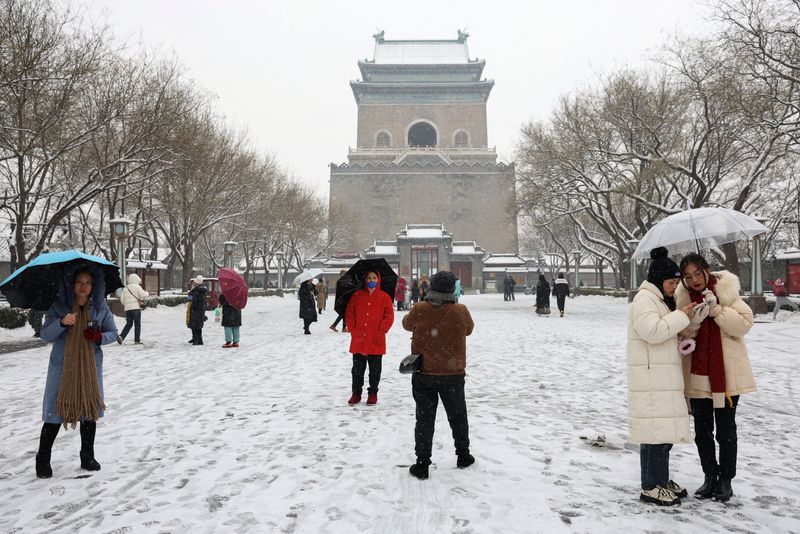 &copy; Reuters. Des gens passent devant la Tour de la Cloche lors de chutes de neige à Pékin, en Chine. /Photo prise le 13 décembre 2023/REUTERS/Tingshu Wang