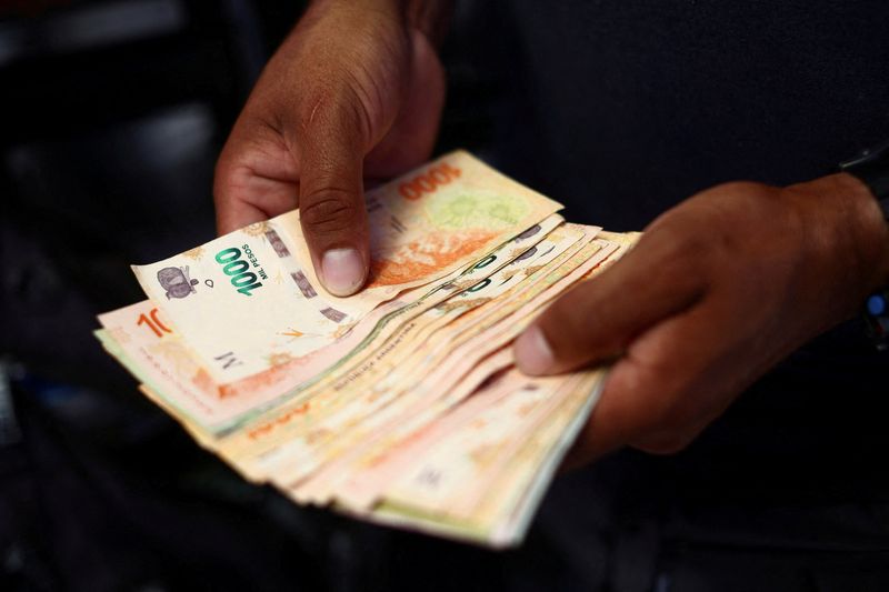 &copy; Reuters. 　アルゼンチン国家統計局が１２月１５日発表した第３・四半期の経済成長率は前年同期比マイナス０．８０％となり、景気後退（リセッション）に突入した。写真は屋台でペソ紙幣を数え