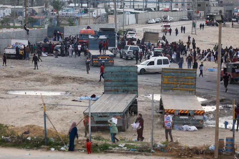 &copy; Reuters. Palestinians gather to unload boxes with bottles of water from trucks, amid drinking water shortages, as the ongoing conflict between Israel and the Palestinian Islamist group Hamas continues, at Rafah border with Egypt, in the southern Gaza Strip Decembe