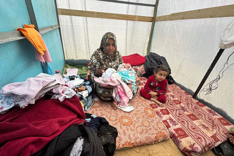 © Reuters. La abuela de Salma y Alma Al-Jadba, dos gemelas palestinas nacidas durante el conflicto entre Israel y Hamás, las sostiene en una tienda de campaña donde se refugian con su familia desplazada que huyó de su casa debido a los ataques israelíes, en Rafah, en el sur de la Franja de Gaza. 17 de diciembre de 2023. REUTERS/Fadi Shana 