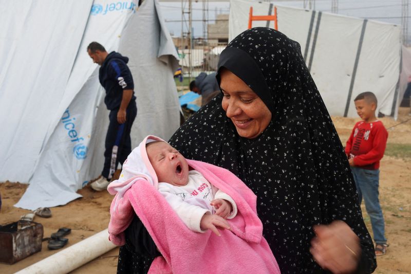 © Reuters. ميرفت صالحة جدة الطفلة الفلسطينية مريم التي ولدت أثناء الحرب بين إسرائيل وحركة حماس تحملها خارج خيمة في رفح بجنوب قطاع غزة يوم الأحد. تصوير: صالح سالم - رويترز.