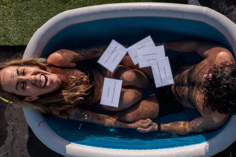 © Reuters. Marcela Bossia of Brazil laughs in an ice bath with Aryan Vavani of New York, as people plunge into baths of freezing cold water to help break the ice while speed dating, in Santa Monica, California, U.S., December 16, 2023.  REUTERS/Mike Blake/File Photo
