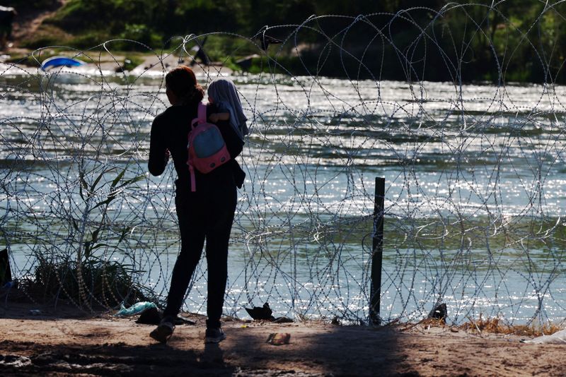 &copy; Reuters. A migrant waits for others after crossing the Rio Grande and getting over the razor wire in Eagle Pass, Texas, U.S., September 29, 2023.   REUTERS/Brian Snyder/ File Photo