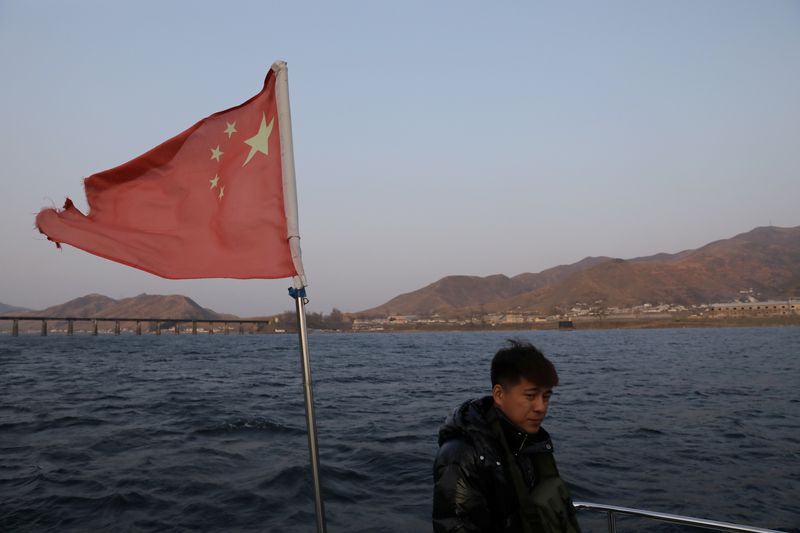 &copy; Reuters. A man stands near a fluttering Chinese national flag on a cruise boat on the Yalu River separating North Korea and China, in Dandong, Liaoning province, China April 20, 2021. Picture taken April 20, 2021. REUTERS/Tingshu Wang/Files