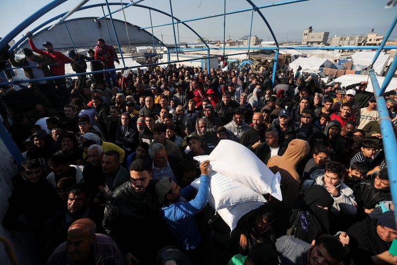&copy; Reuters. فلسطينيون يتسلمون أكياس طحين وزعتها وكالة الأمم المتحدة لإغاثة وتشغيل اللاجئين (الأونروا) خلال هدنة مؤقتة بين حماس وإسرائيل في خان يونس بجن