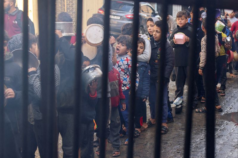 © Reuters. Niños palestinos hacen cola para recibir comida de una cocina de caridad, en medio de la escasez de suministros de alimentos, mientras continúa el conflicto entre Israel y Hamás, en Rafah en el sur de la Franja de Gaza. 14 de diciembre 2023. REUTERS/Saleh Salem