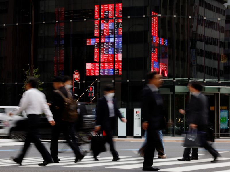 &copy; Reuters. FILE PHOTO: Pedestrians walk past an electronic board displaying various companies' share prices, at a business district in Tokyo, Japan, October 31, 2023. REUTERS/Kim Kyung-Hoon/File photo