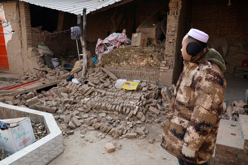 © Reuters. A man stands at his damaged house at Sibuzi village following the earthquake in Jishishan county, Gansu province, China December 21, 2023. REUTERS/Xiaoyu Yin