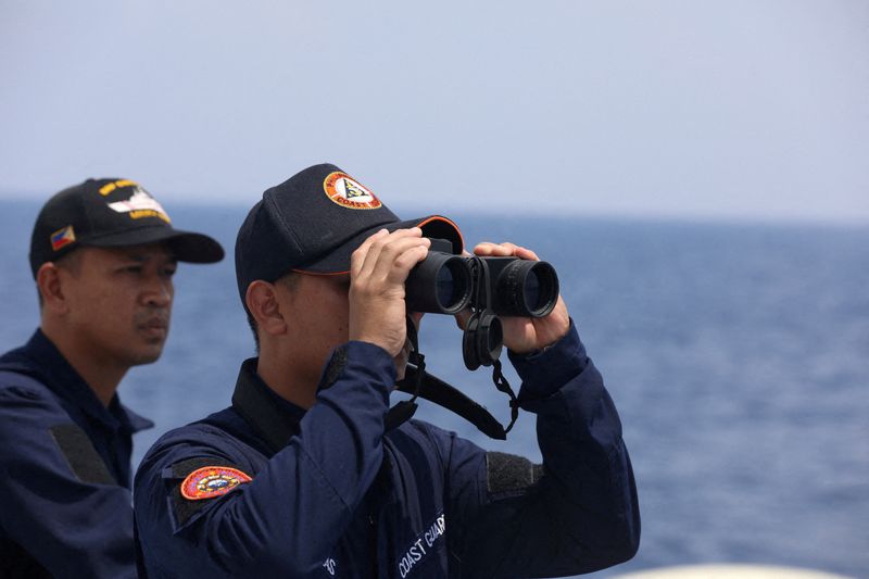 © Reuters. FOTO DE ARCHIVO: Un personal de la Guardia Costera de Filipinas mira a través de un binocular mientras realiza una misión de reabastecimiento para las tropas filipinas estacionadas en un buque de guerra varado en el Mar de China Meridional, 4 de octubre de 2023. REUTERS/Adrian Portugal/File Photo 