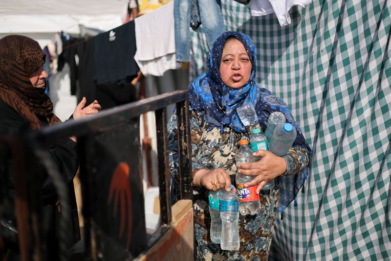 &copy; Reuters. امرأة فلسطينية تحمل زجاجات مياه وسط الصراع المستمر بين إسرائيل وحركة المقاومة الإسلامية الفلسطينية (حماس) في رفح بجنوب قطاع غزة يوم الثامن 