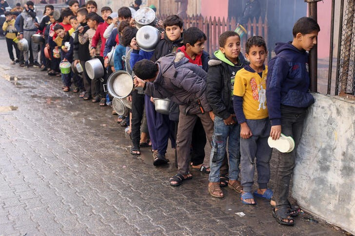 &copy; Reuters. Niños palestinos llevan potes vacíos mientras hacen fila para recibir alimentos de grupos de ayuda humanitaria mientras continúa el conflicto entre Israel y el grupo Hamas en la Franja de Gaza.  Diciembre 14, 2023. REUTERS/Saleh Salem