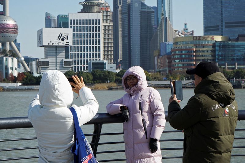 &copy; Reuters. أشخاص يرتدون معاطف يلتقطون صورا في شنغهاي بالصين يوم  الخميس. تصوير: نيكوكو تشان - رويترز.