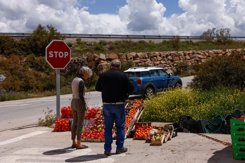&copy; Reuters. A fruit and vegetable vendor servers to a woman on a road in Ardales, near Malaga, Spain, April 28, 2022. REUTERS/Jon Nazca/file photo