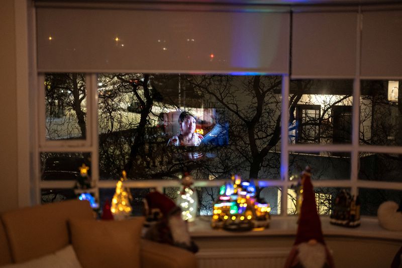 &copy; Reuters. Una pantalla de televisión se ilumina en la ventana de un salón mientras Kristin Maria Birgisdottir, de 43 años, su hijo Thordur Halldor Stefansson, de 9, su madre Kristin Arnberg, de 71, su padre Birgir Sigurdsson, de 71, se preparan para la Navidad e
