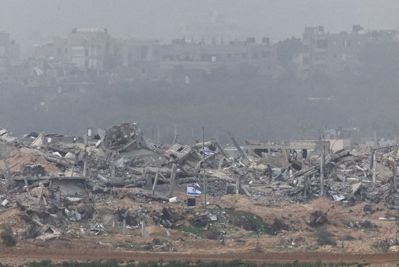 © Reuters. Israeli flags fly next to the rubble of destroyed buildings in Gaza, amid the ongoing conflict between Israel and the Palestinian Islamist group Hamas, as seen from southern Israel, December 23, 2023. REUTERS/Violeta Santos Moura