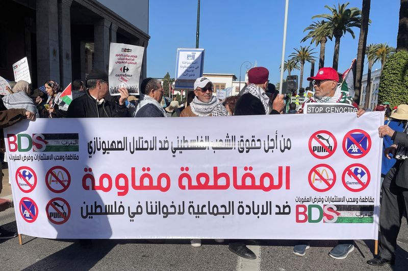 &copy; Reuters. متظاهرون يحملون لافتة تظهر علامات تجارية عاملية لمقاطعتها خلال المسيرات المؤيدة للفلسطينيين في الرباط يوم الأحد. تصوير: أحمد الشجتيمي - روي
