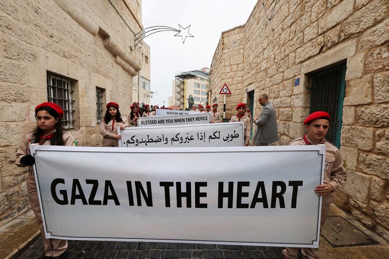 &copy; Reuters. أفراد من الكشافة في الضفة الغربية يحملون لافتة تضامنية مع الفلسطينيين في غزة، يوم زيارة بطريرك القدس اللاتيني بيير باتيستا بيتسابلا للبلدة