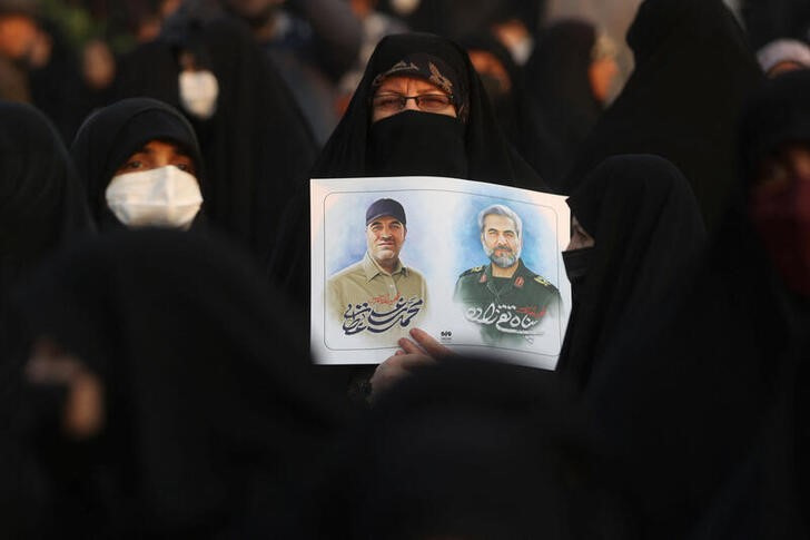 &copy; Reuters. Imagen de archivo de una mujer mostrando las fotos de Panah Taghizadeh y Mohammad-Ali Ataie, dos miembros de la Guardia Revolucionaria Iraní muertos en un ataque aéreo israelí en Siria, durante su funeral en Teherán, Irán. 4 diciembre 2023. Majid Asg