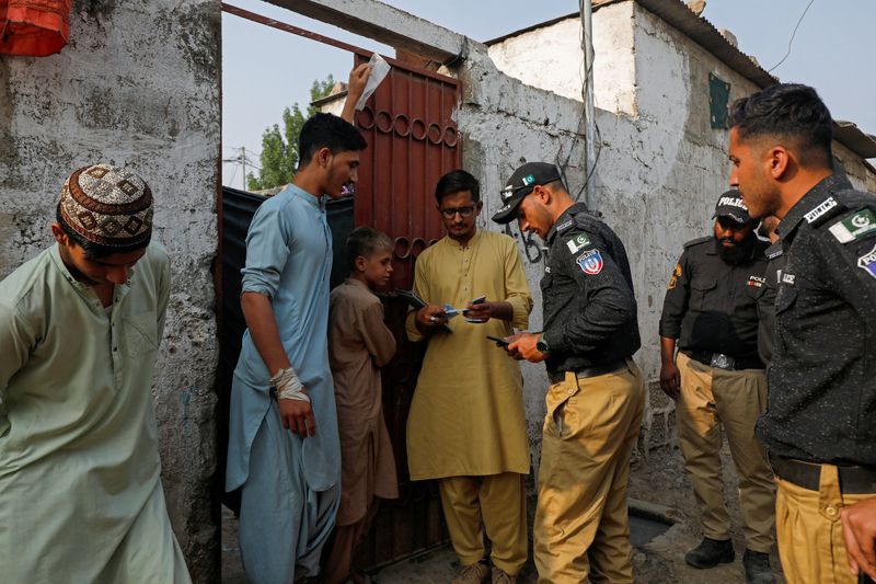 &copy; Reuters. FILE PHOTO: Police officers, along with workers from the National Database and Registration Authority (NADRA), check the identity cards of Afghan citizens during a door-to-door search and verification drive for undocumented Afghan nationals, in an Afghan 