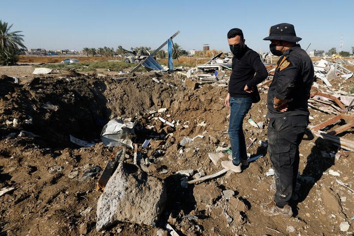 &copy; Reuters. Un combatiente de la milicia Kataib Hezbolá y otra persona inspeccionan el lugar de un ataque aéreo de EEUU en Hilla, Irak. 26 diciembre 2023. REUTERS/Alaa al-Marjani