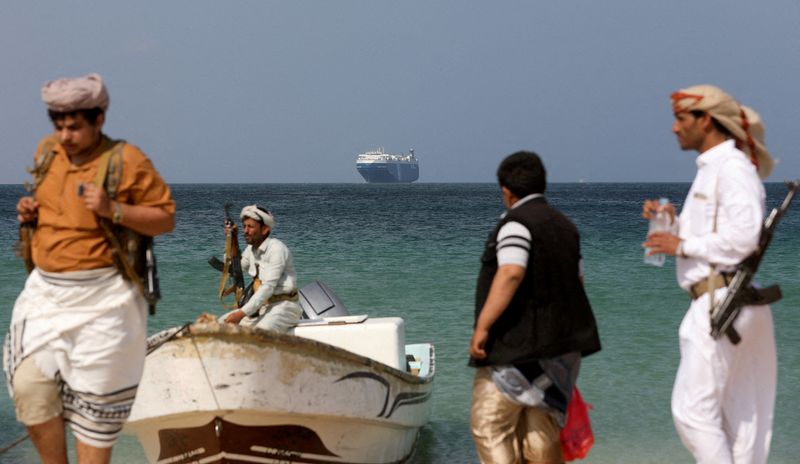 © Reuters. مسلحون يقفون على الشاطئ بينما تظهر في عرض البحر سفينة (جالاكسي ليدر) التجارية التي استولى عليها الحوثيون في نوفمبر تشرين الثاني 2023 وهي تقف قبالة ساحل الصليف باليمن يوم 5 ديسمبر كانون الأول 2023. تصوير: خالد عبد الله - رويترز 