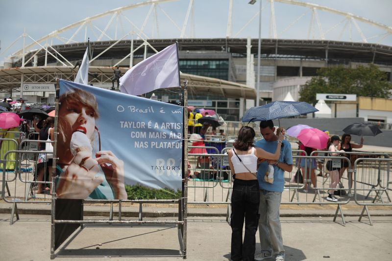 &copy; Reuters. Casal se protege do forte calor enquanto aguarda show da cantora norte-americana Taylor Swift, no Rio de Janeiro
18/11/2023 REUTERS/Pilar Olivares