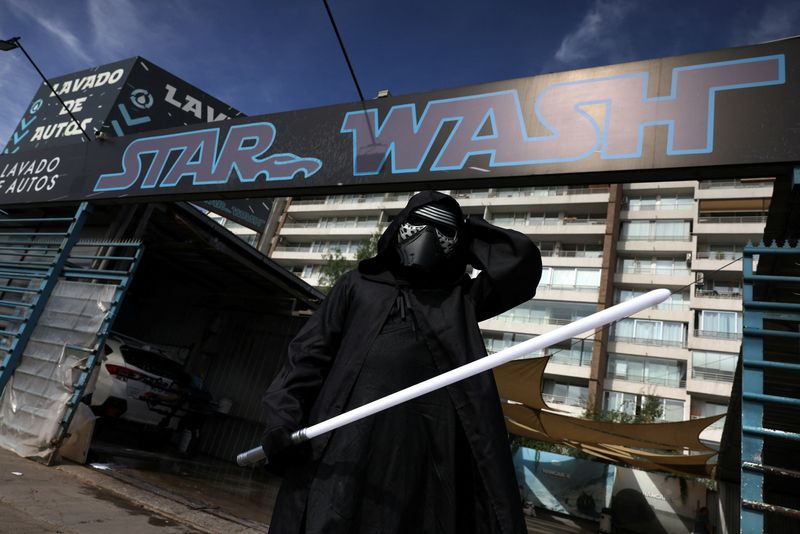 © Reuters. Un empleado vestido como un personaje de 'Star Wars' espera a los clientes frente a una pancarta en la que se lee 'Star Wash', que es un juego de palabras con 'Star Wars', en un servicio de lavado de automóviles temático en Santiago, Chile. 26 de diciembre de 2023. REUTERS/Iván Alvarado