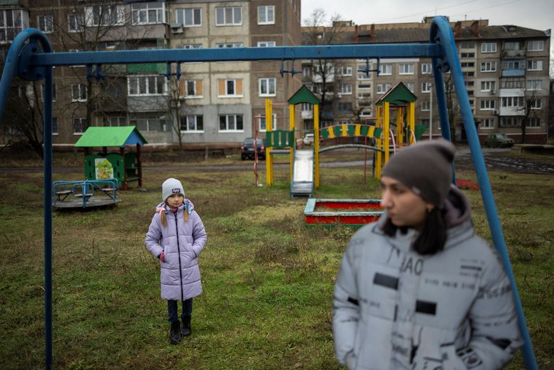 © Reuters. Iryna and her daughter, third-grader Arina, stand in a playground after an online reading class in Sloviansk, amid Russia's attack on Ukraine, December 20, 2023. Ukrainian third-grade student Arina has had just over 1,5 months of in-class schooling because of the war that poses the regular threat of Russian air strikes on schools.  REUTERS/Thomas Peter