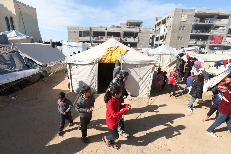&copy; Reuters. فلسطينيون يمرون من أمام خيمة، وسط الصراع بين إسرائيل وحركة المقاومة الإسلامية حماس، في رفج جنوب قطاع غزة يوم 24 ديسمبر كانون الأول 2023. تصوير: 