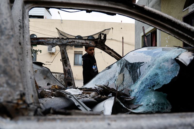 © Reuters. A Palestinian boy looks at a destroyed car, in the aftermath of an Israeli raid in Nour Shams camp, in Tulkarm, in the Israeli-occupied West Bank, December 27, 2023. REUTERS/Raneen Sawafta