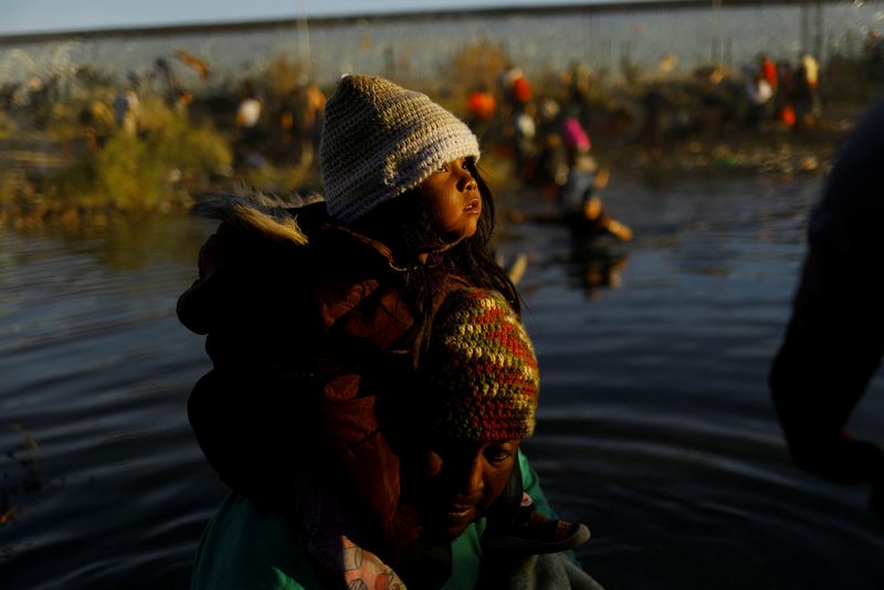 © Reuters. Teo, a Venezuelan migrant, carries his daughter Sharill as they cross the Rio Bravo river, the border between the United States and Mexico, with the intention of turning themselves in to the U.S. Border Patrol agents to request asylum, during a day of low temperatures, as seen from Ciudad Juarez, Mexico December 28, 2023. REUTERS/Jose Luis Gonzalez
