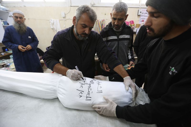 &copy; Reuters. Mohammed Abu Mussa, voluntário, escreve em mortalha de vítima palestina de um ataque de Israel a Gaza
08/12/2023
REUTERS/Ibraheem Abu Mustafa