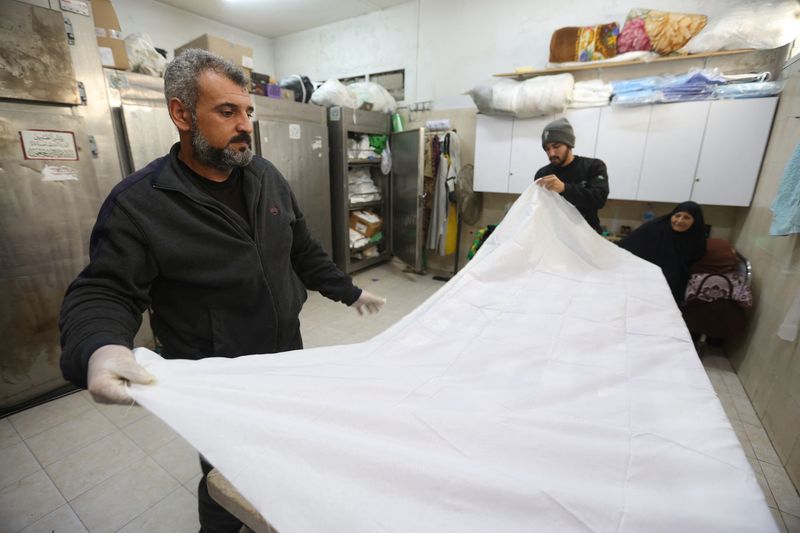 &copy; Reuters. Mohammed Abu Mussa, voluntario de la sociedad Keratan que prepara cadáveres para su entierro, prepara un sudario blanco, en medio del actual conflicto entre Israel y el grupo islamista palestino Hamás, en un hospital de Rafah, sur de la Franja de Gaza. 