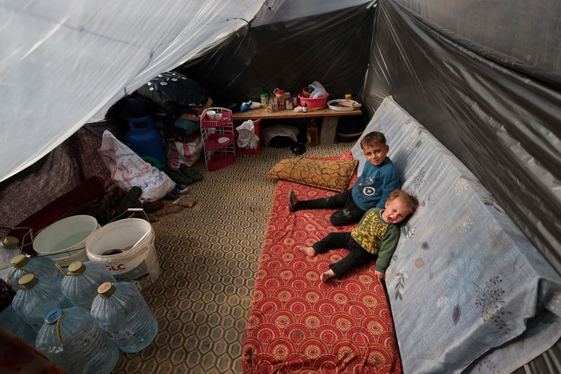 © Reuters. Niños palestinos desplazados, que huyeron de sus hogares debido a los ataques israelíes, se refugian en un campamento de tiendas de campaña, en medio del conflicto en curso entre Israel y el grupo islamista palestino Hamás, en Rafah, sur de la Franja de Gaza, 29 de diciembre de 2023. REUTERS/Ibraheem Abu Mustafa    