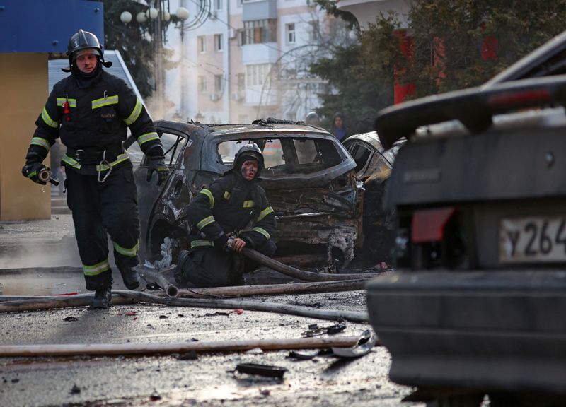 &copy; Reuters. رجلان إطفاء يعملون على إطفاء السيارات المحترقة في أعقاب ما تقول السلطات الروسية إنها ضربة عسكرية أوكرانية في بيلجورود يوم السبت. صورة لرويت